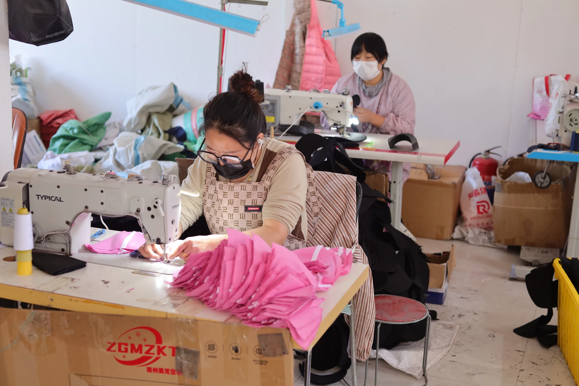 Operators sewing fabric components at the cap production workstations