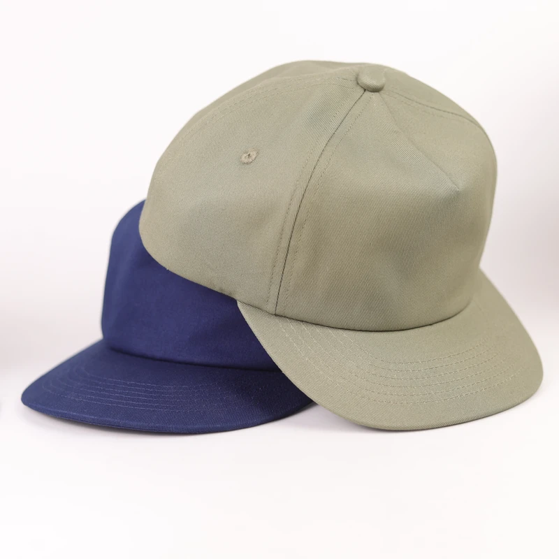 Khaki compact-brim cap in front of a separate blue sample