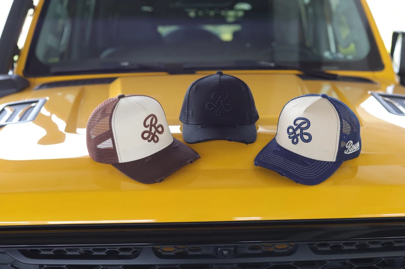 Three colorway distressed mesh caps arranged together on yellow vehicle