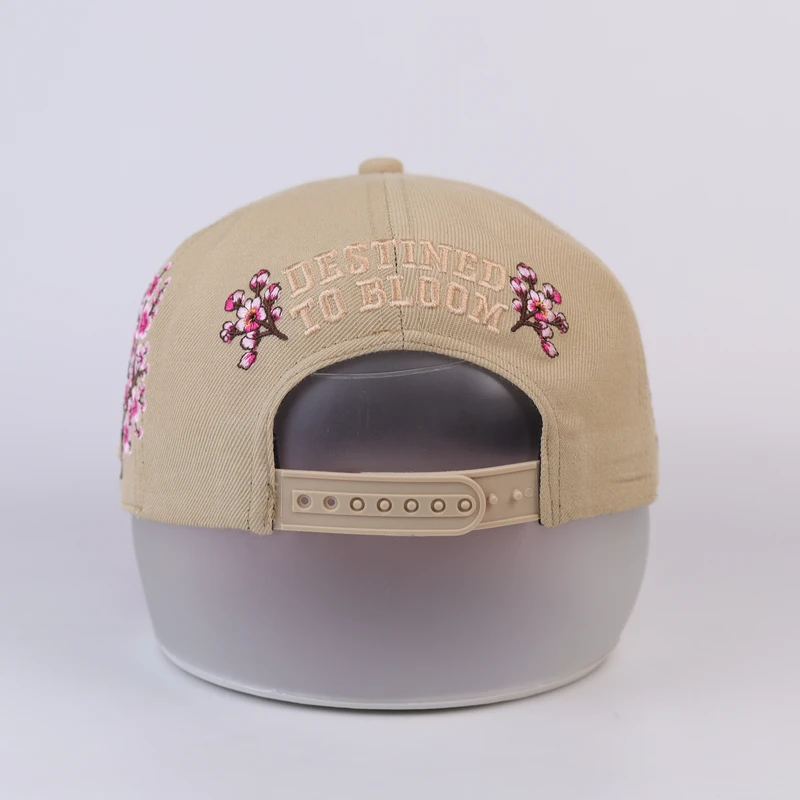 Rear of khaki cap with small blossom embroidery around snapback opening