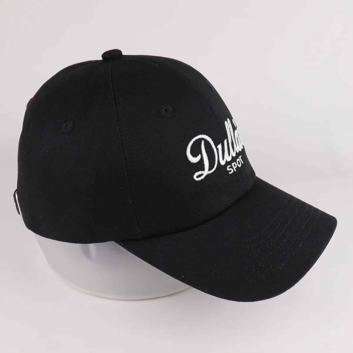 Three-quarter view of a black baseball cap with white script embroidery