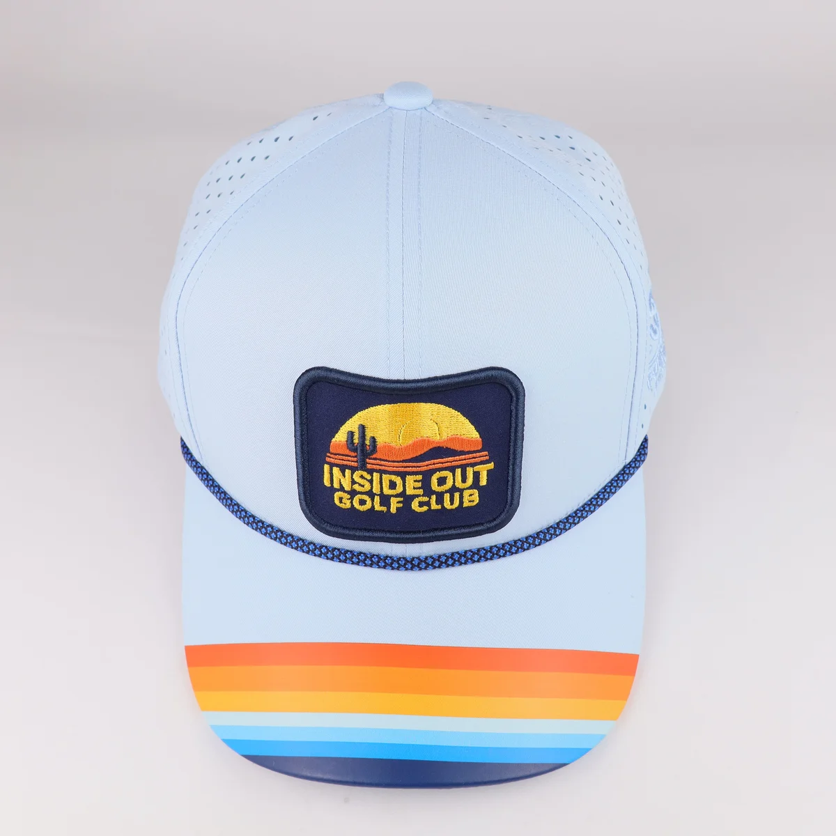 Top-front view of light blue cap showing curved rows of multicolor visor artwork